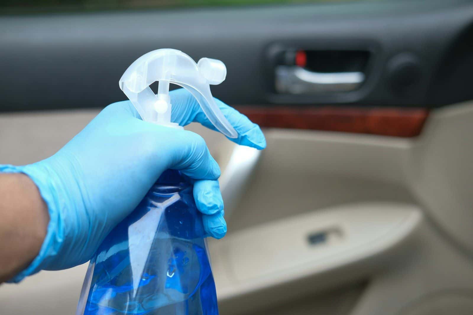 Auto-interieur wordt gereinigd met een sproeiflacon en handschoenen
